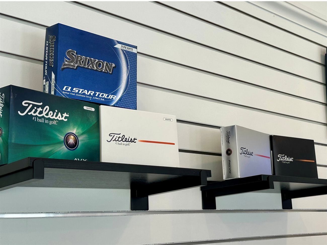 Titleist and Srixon golf ball boxes on a shelf